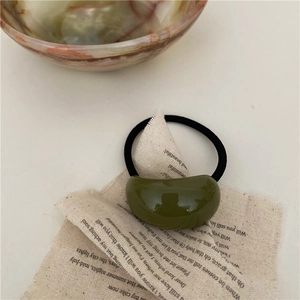 Détail d'un chouchou géométrique en résine vert olive sur fond de tissu en lin épuré