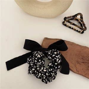 Elegant leopard print bow scrunchie and geometric hair claw clip set on minimalist background