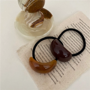 Détail d'élastiques à cheveux en résine ambre sur un fond de tissu vintage