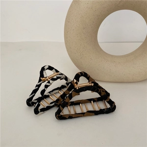 Detail of leopard and zebra print hair claws with gold metal teeth on beige background