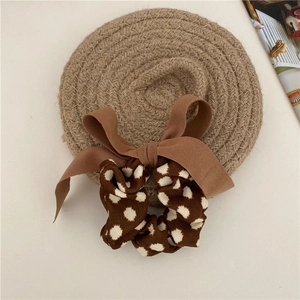 Detail of elegant brown polka dot hair scrunchie with large bow on woven mat
