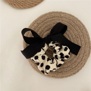 Detail of elegant black ribbon bow scrunchie with classic polka dot pattern texture