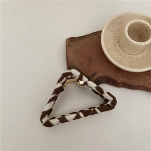 Close-up of a retro triangular hair claw clip with brown and white checkered woven fabric