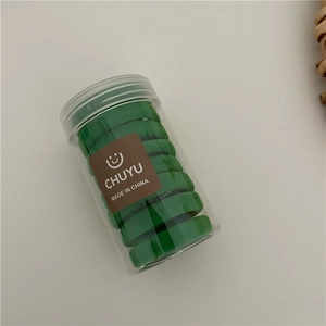Close-up of vibrant green elastic hair ties packed in a clear jar with a smiley face logo