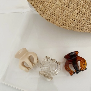 Three medium claw clips in cream, clear, and tortoiseshell resin on white tray