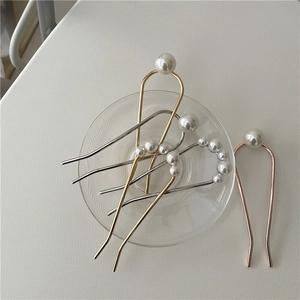 Detail of U-shaped hairpins in gold and silver with elegant white pearls and glossy finish