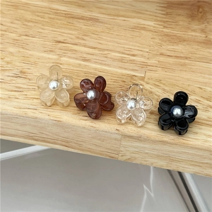 Detailset van vier mini bloem haarklemmen met parels op een rustieke houten textuur achtergrond