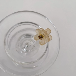 Detail van mini amberkleurige bloem haarklem met strass op een glazen rand