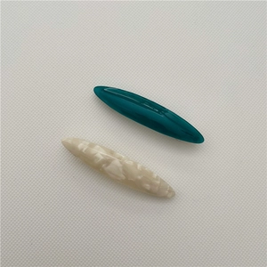 Detail of dark green and marble white acetate leaf hair clips on grid background