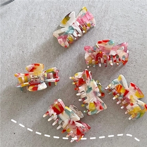 Detailed top view of 6-piece acrylic hair claws with colorful marble texture and metal spring
