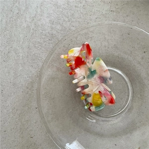 Detail of a bow-shaped hair claw with vintage marble texture in a glass bowl