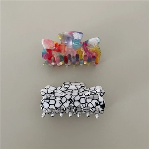 Detailed macro view of acetate hair claws featuring colorful oil painting and marble patterns