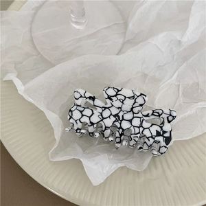 Macro shot of marble pattern hair claw on textured white background in minimalist style