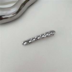 Dettaglio di un fermaglio per capelli in metallo argento con design a catena cubana