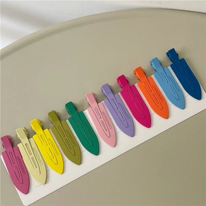 Detailed macro shot of eleven colorful matte duckbill hair clips arranged on white card
