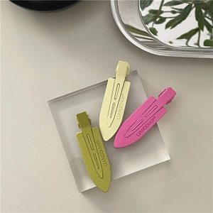 Detailed view of matte neon duckbill hair clips in olive green, pale yellow and rose pink
