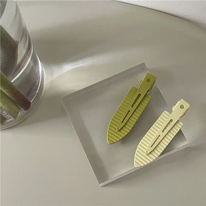Neon matte olive green and beige hair clips for bangs shown on a stylish display stand