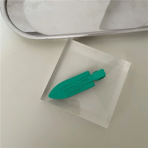 Detail of neon green seamless hair clip with matte finish and engraved logo on metal