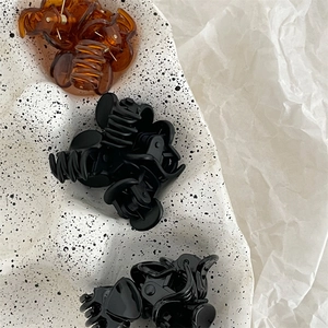 Mini pinces à cheveux en noir mat et écaille de tortue ambrée sur plateau blanc