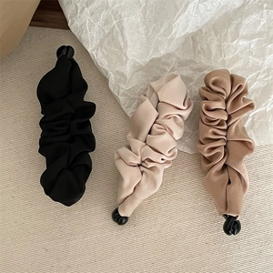 Detailed view of banana hair clips in black, beige, and camel elegant pleated fabric