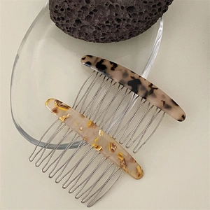 Close-up of tortoise shell and marble textured hair side combs with metal teeth set