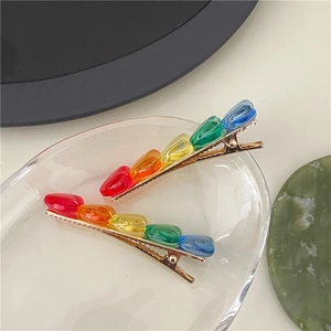 Dettaglio di due fermagli per capelli a cuore arcobaleno su base in lega dorata