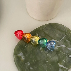 Dettaglio molletta per capelli a cuore in resina arcobaleno su vassoio marmo