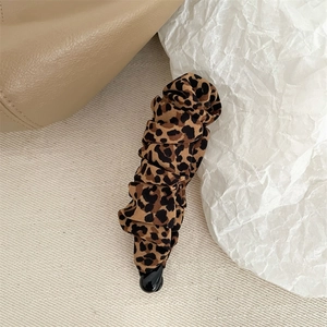 Close-up of leopard print fabric banana hair clip with elegant pleats on beige background