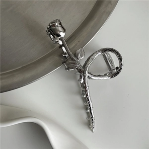 Detailed view of silver metallic rose hair claw clip with intricate thorn texture and spring