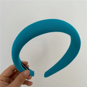 Detail of thick peacock blue sponge headband featuring a handmade woven label