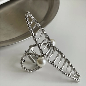 Detail of silver twisted metal hair claw clip featuring elegant pearl embellishments