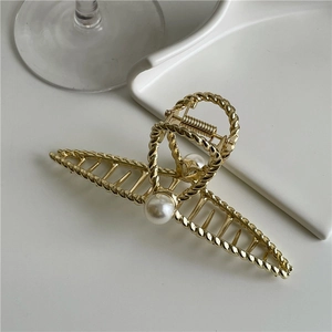 Detailed view of elegant gold metal hair claw with twisted texture and large pearls
