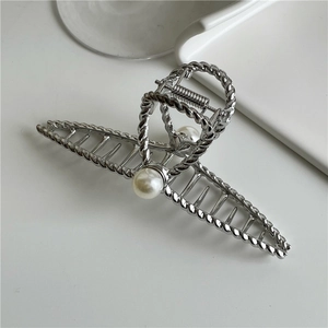 Detail of silver metal hair claw featuring twisted rope texture and large white pearls