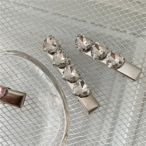 Dettaglio ravvicinato di un fermaglio argento con tre brillanti strass a forma di cuore