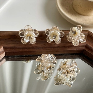 Mini pinces à cheveux fleuries avec perles et strass sur une surface de miroir vintage
