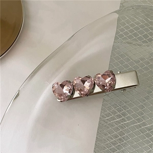 Dettaglio del fermaglio per capelli in argento con tre cristalli a cuore rosa e becco