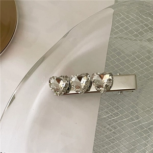 Vista dettagliata del fermaglio in metallo argento con tre brillanti cristalli a cuore