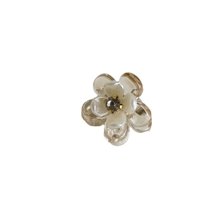 Mini pince à cheveux fleurie avec finition perle et strass central sur fond blanc