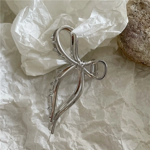 Dettaglio di un fermaglio per capelli a farfalla argento con molla in metallo