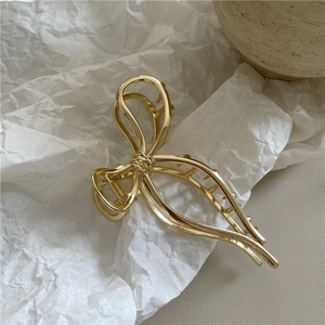 Dettaglio dell'elegante molletta per capelli in metallo dorato su carta testurizzata