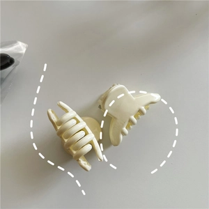 Close-up of two mini cream white jelly plastic hair claws with polished finish