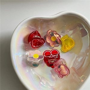 Détail de 6 mini pinces à cheveux fruits avec finition irisée dans un plat en cœur