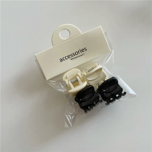 Detail of four mini jelly hair clips in black and cream colors with card packaging