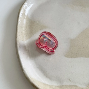 Détail d'une pince à cheveux cerise rose posée sur un plateau en céramique