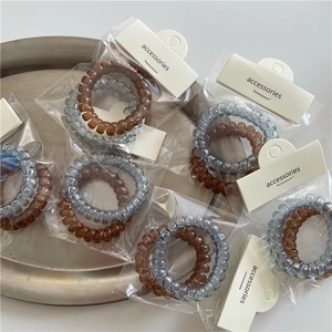 Detalle de las gomas de pelo en espiral grises y marrones en envase de cartón