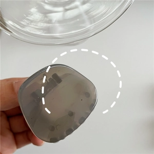 Close-up of a translucent grey geometric triangle hair claw clip held by a person