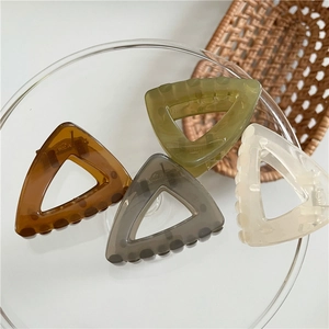 Detailed view of four colorful geometric triangle hair claws on a glass plate
