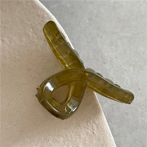 Close-up of olive green jelly hair claw clip with marble texture and cross design