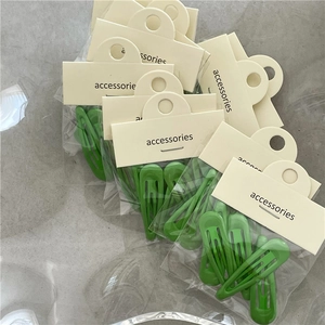Détail des barrettes BB vert vif présentées dans leur emballage cartonné d'origine