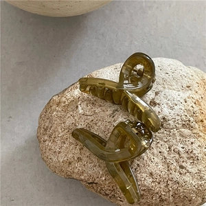 Close-up of translucent jelly-colored hair clips in olive green and amber on a stone
